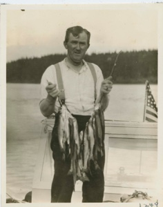Image: Martin Vorse (cook) standing on the cabin of Seeko with trout caught in Frank's